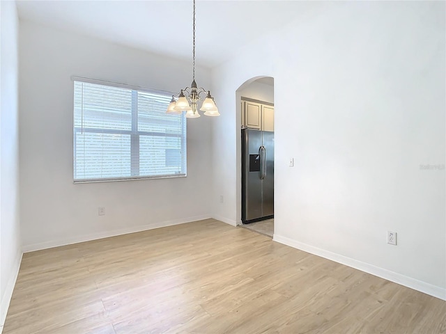 spare room featuring light hardwood / wood-style floors and a chandelier