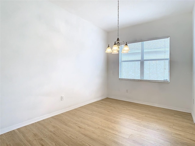 spare room with a chandelier and light hardwood / wood-style floors