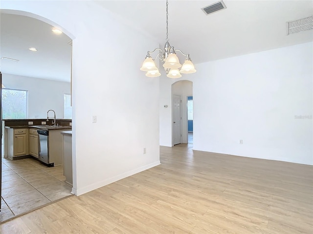 empty room with sink, light hardwood / wood-style flooring, and an inviting chandelier