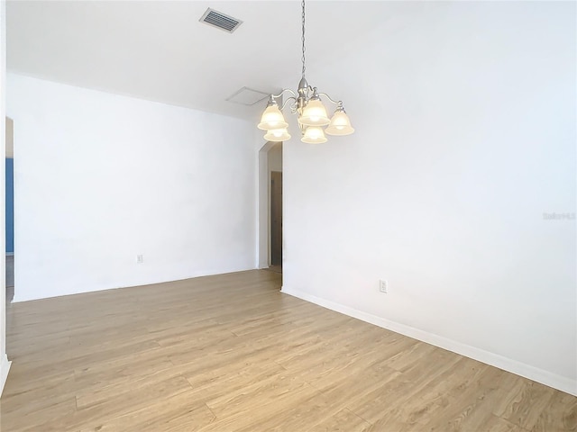 empty room with light wood-type flooring and an inviting chandelier