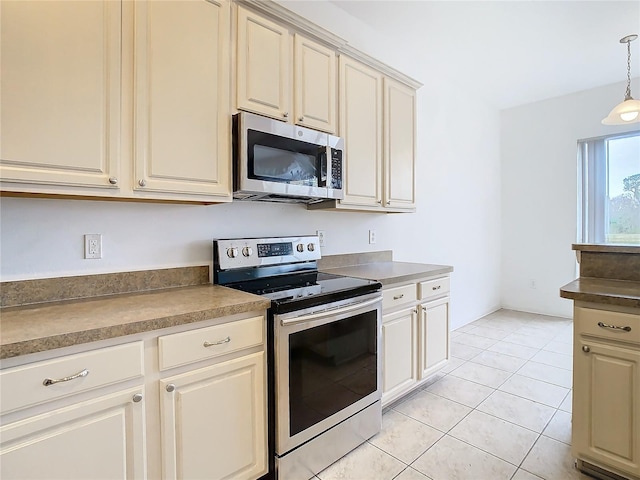 kitchen featuring pendant lighting, light tile patterned floors, stainless steel appliances, and cream cabinetry