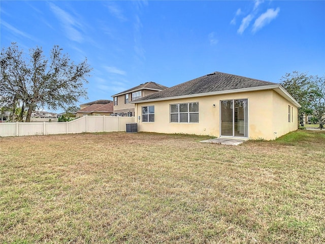 back of house with central AC unit and a lawn