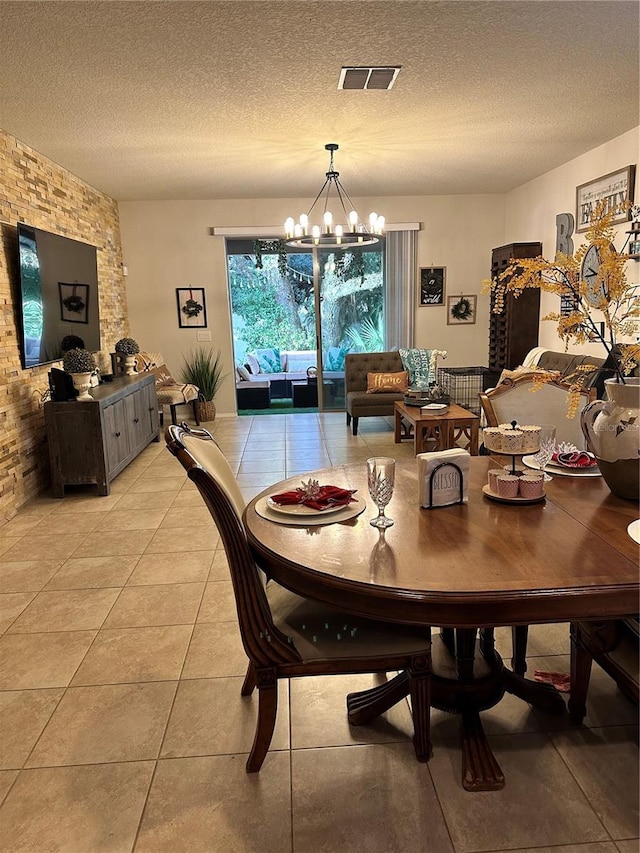 dining space with light tile patterned flooring, a textured ceiling, and a chandelier