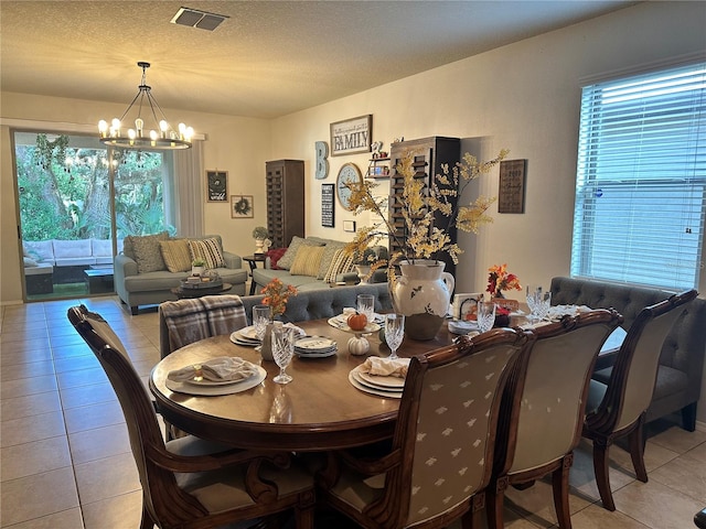 tiled dining area with a textured ceiling and an inviting chandelier