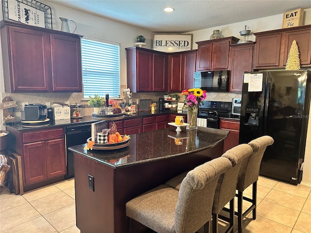 kitchen with tasteful backsplash, black appliances, a center island, and light tile patterned flooring