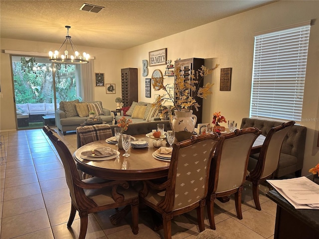 dining room featuring a textured ceiling, light tile patterned flooring, and a chandelier