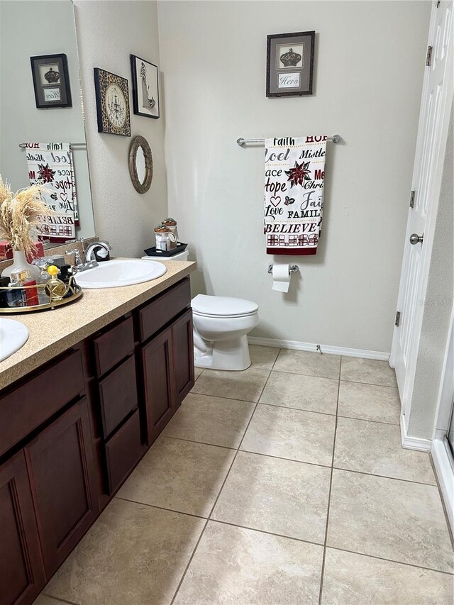 bathroom with toilet, vanity, and tile patterned flooring