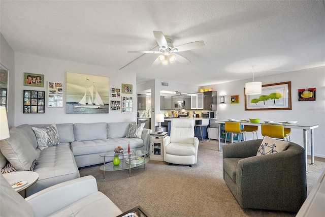 living room featuring carpet floors, a textured ceiling, and ceiling fan