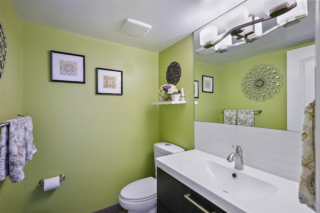 bathroom with vanity, toilet, and decorative backsplash