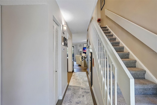 hall featuring a textured ceiling and light hardwood / wood-style flooring