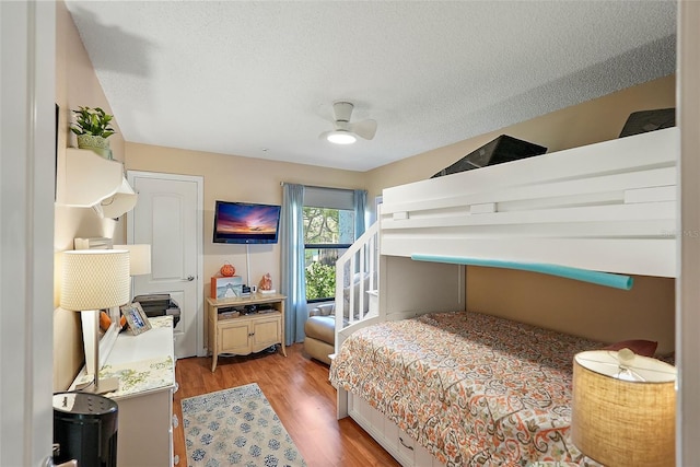 bedroom with a textured ceiling, light hardwood / wood-style flooring, and ceiling fan