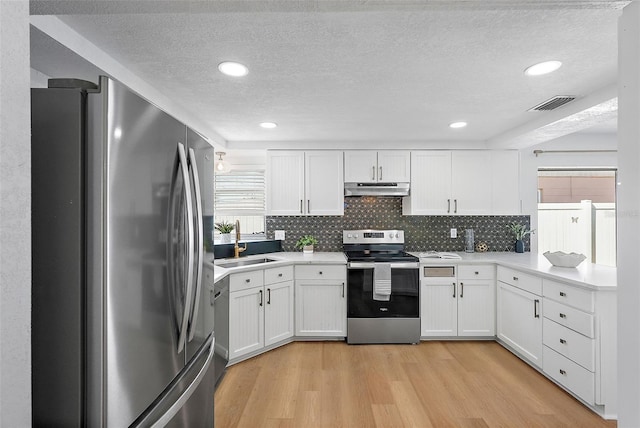 kitchen featuring white cabinetry, sink, tasteful backsplash, light hardwood / wood-style floors, and appliances with stainless steel finishes