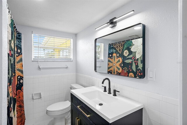 bathroom with vanity, tile walls, and toilet