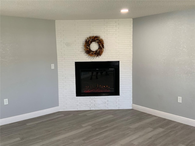 room details featuring a textured ceiling, hardwood / wood-style flooring, and a brick fireplace