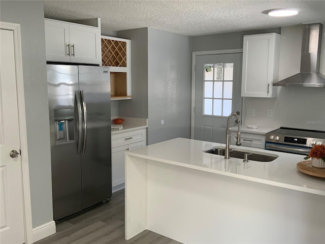 kitchen featuring wall chimney range hood, white cabinets, appliances with stainless steel finishes, a textured ceiling, and dark hardwood / wood-style floors