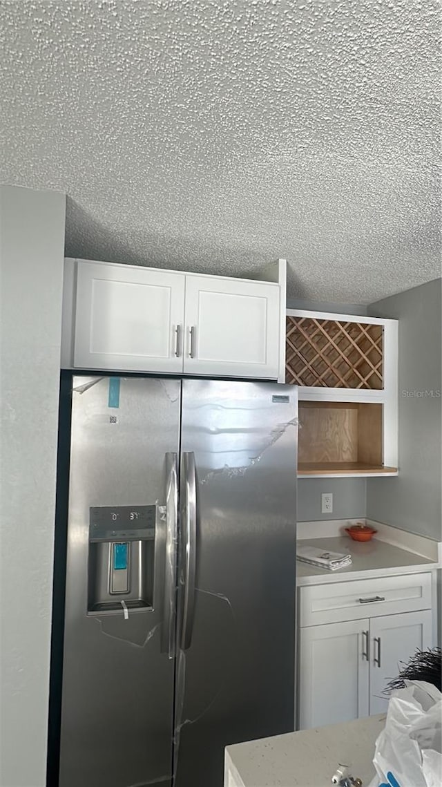 kitchen featuring white cabinetry, a textured ceiling, and stainless steel fridge