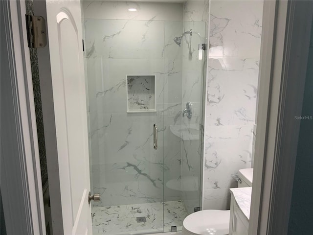 bathroom featuring vanity, a shower with shower door, and toilet