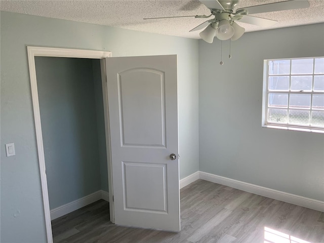 unfurnished bedroom with a closet, ceiling fan, hardwood / wood-style flooring, and a textured ceiling