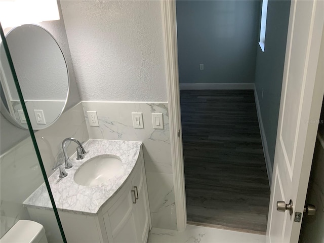 bathroom with tile walls, vanity, hardwood / wood-style floors, and toilet