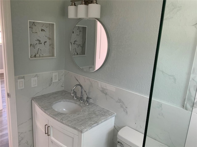 bathroom featuring tile walls, vanity, and toilet