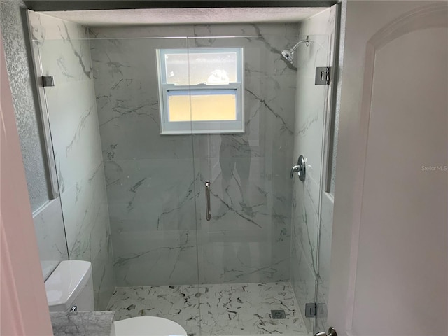 bathroom featuring a shower with door and toilet