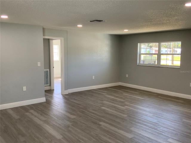 empty room featuring dark wood-type flooring and a textured ceiling