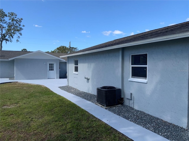 view of side of property with central AC unit and a lawn