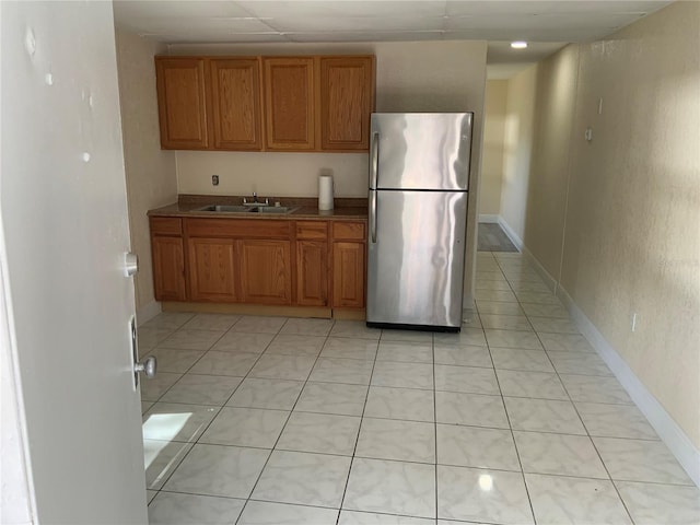 kitchen with light tile patterned floors, stainless steel refrigerator, and sink