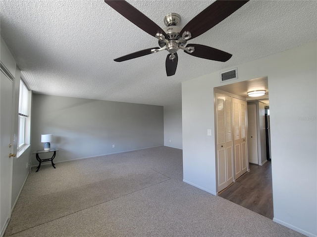 unfurnished room featuring ceiling fan, a textured ceiling, and dark colored carpet