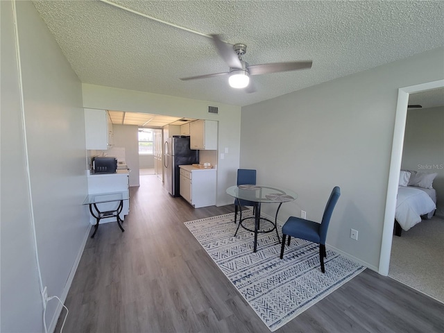 dining room featuring a textured ceiling, wood-type flooring, and ceiling fan