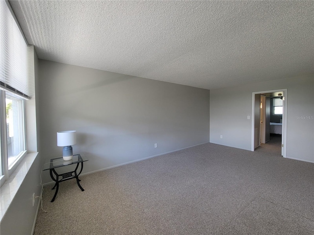 carpeted empty room featuring a textured ceiling