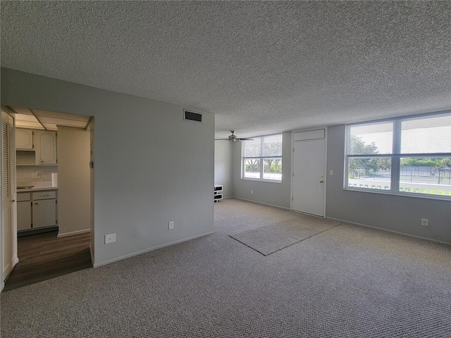 empty room with ceiling fan, light carpet, and a textured ceiling