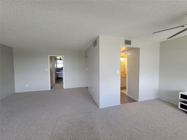 carpeted empty room with ceiling fan and a textured ceiling