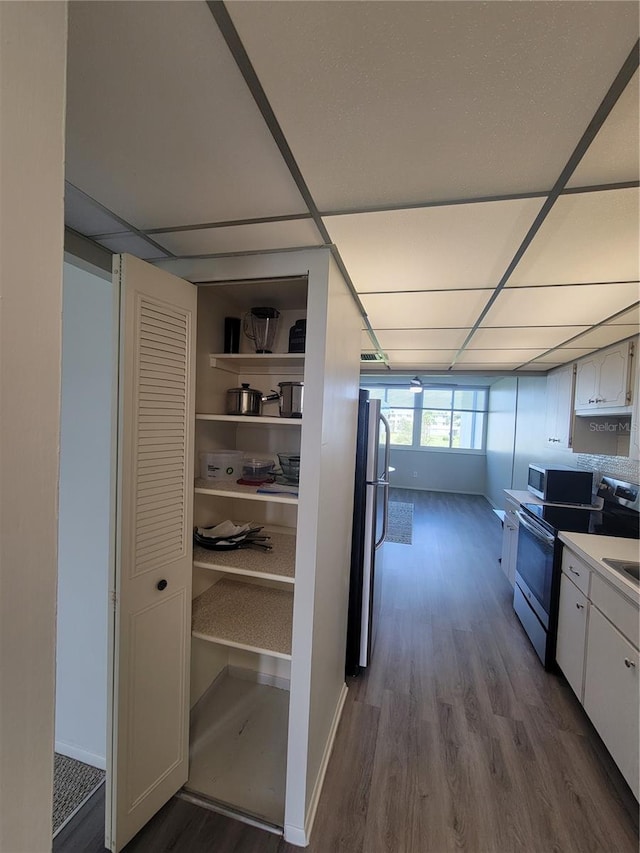 interior space featuring appliances with stainless steel finishes, white cabinets, and wood-type flooring