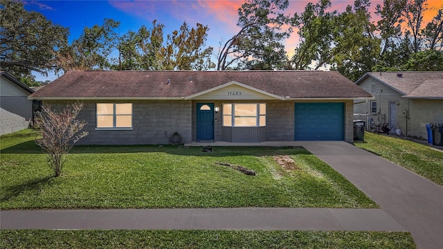 ranch-style house with a garage and a lawn