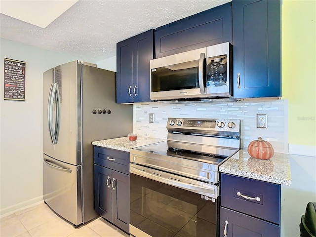 kitchen featuring light tile patterned flooring, blue cabinets, stainless steel appliances, and backsplash