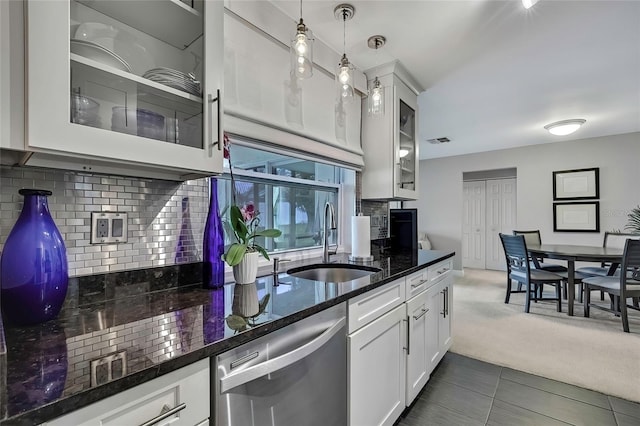 kitchen with sink, stainless steel dishwasher, decorative light fixtures, white cabinets, and dark tile patterned flooring