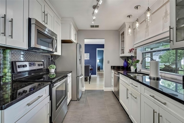 kitchen with white cabinetry, sink, stainless steel appliances, and decorative light fixtures