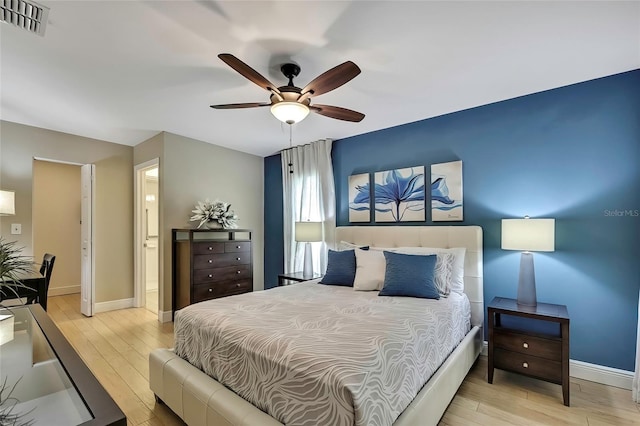 bedroom featuring ceiling fan, light wood-type flooring, and ensuite bath