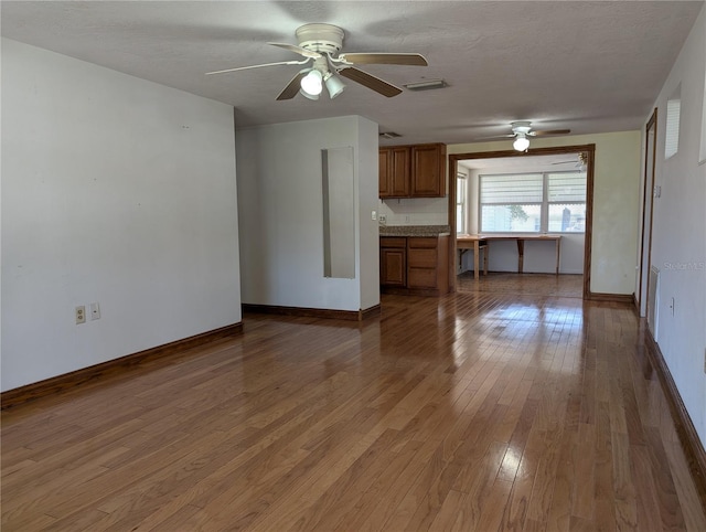 unfurnished living room with ceiling fan, hardwood / wood-style floors, and a textured ceiling