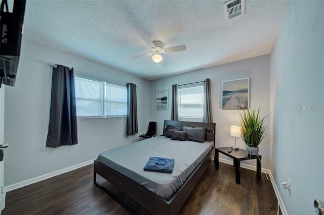 bedroom with multiple windows, a textured ceiling, dark wood-type flooring, and ceiling fan