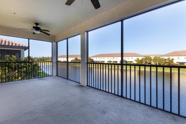 unfurnished sunroom featuring a water view and ceiling fan