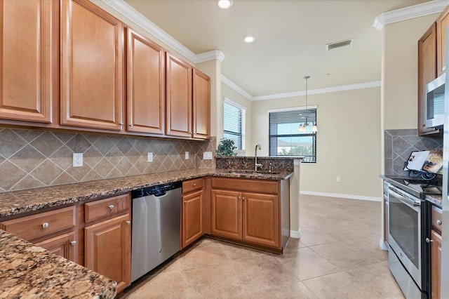 kitchen with pendant lighting, sink, appliances with stainless steel finishes, and dark stone counters