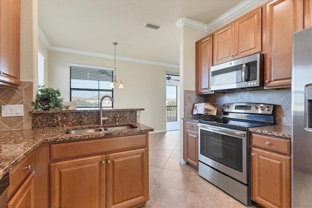 kitchen featuring dark stone counters, stainless steel appliances, sink, light tile patterned floors, and hanging light fixtures