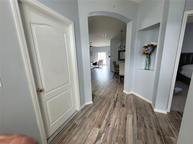 corridor with a notable chandelier and wood-type flooring