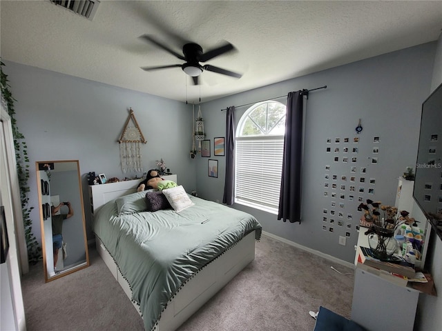 bedroom with ceiling fan, light carpet, and a textured ceiling