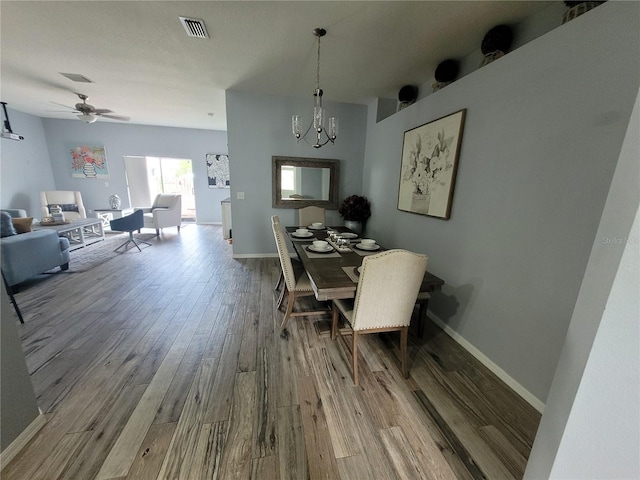 dining area with wood-type flooring and ceiling fan with notable chandelier