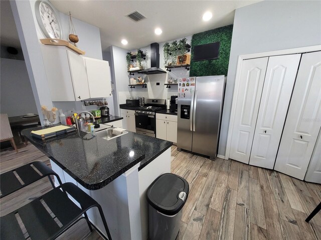 kitchen featuring light hardwood / wood-style floors, white cabinetry, stainless steel appliances, and ventilation hood