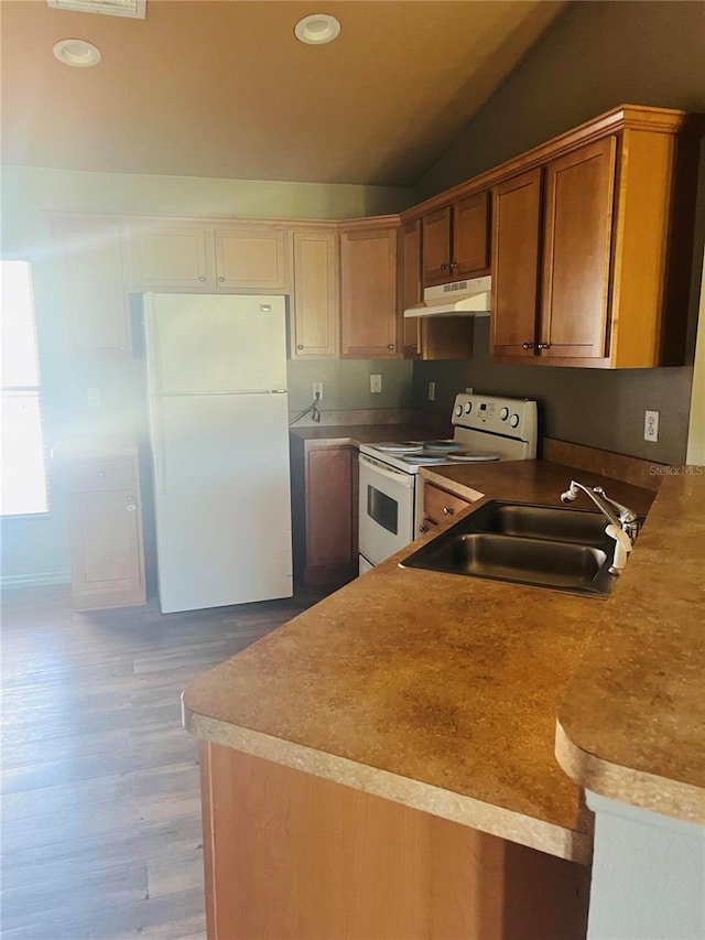 kitchen with kitchen peninsula, hardwood / wood-style flooring, vaulted ceiling, sink, and white appliances