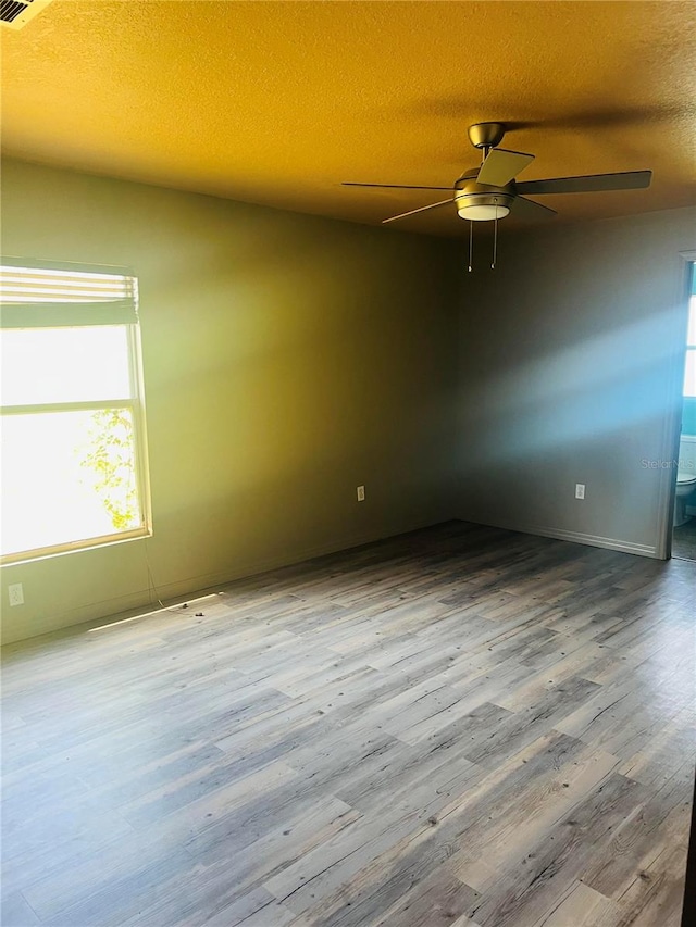 empty room with hardwood / wood-style floors, a textured ceiling, and ceiling fan